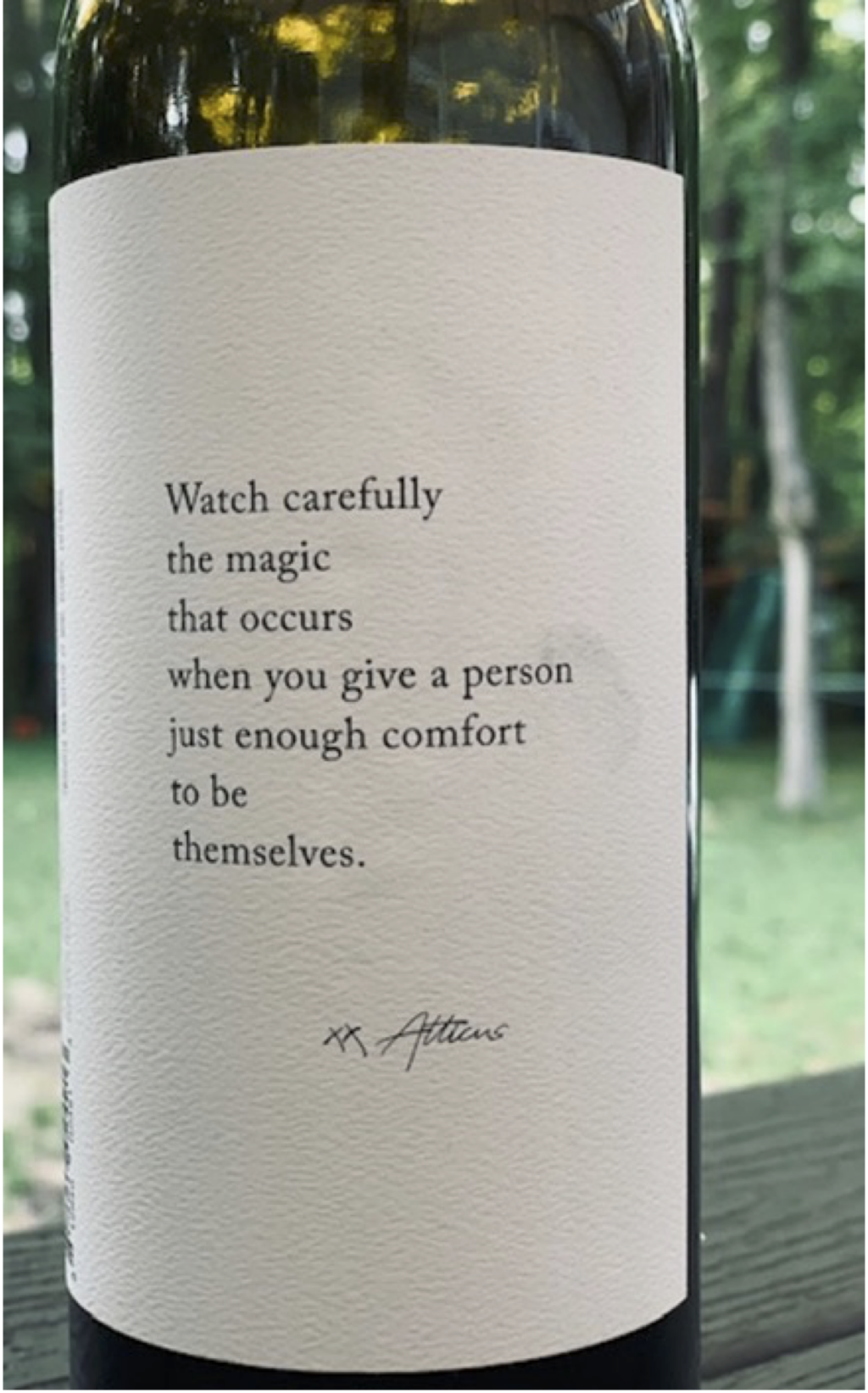 Close-up of a label on a wine bottle. The label reads, "Watch carefully the magic that occurs when you give a person just enough comfort to be themselves."